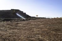 a road is in the middle of desert with rocks in the distance, some bushes and sand are behind