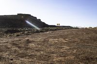 a road is in the middle of desert with rocks in the distance, some bushes and sand are behind