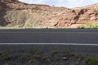 a person riding a motorcycle along a narrow road through rocks and sand cliffs a grassy area on both sides