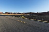 empty desert roadway and mountains, with yellow lines down middle side of street in background