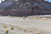 a small road in front of the rocky hills of an empty land with a motorcycle parked on it