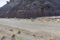 a small road in front of the rocky hills of an empty land with a motorcycle parked on it