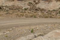 an image of a person on a motorcycle riding along the side of the road in front of mountains