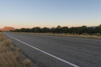 a long empty road with mountains in the distance with a car in the foreground