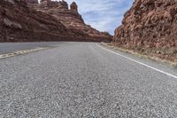 the empty road stretches out into the distance and extends into a large canyon with sparse rock formations