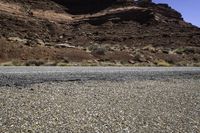 the road is surrounded by rocks and desert scrubs that are very barren and rocky