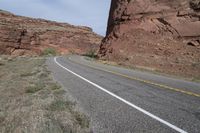 a person riding a motorcycle along a narrow road through rocks and sand cliffs a grassy area on both sides