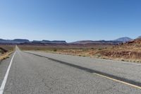 a lone car is driving on a desert highway with mountains in the background of the road