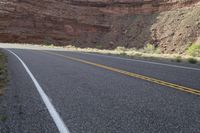 a person riding a motorcycle along a narrow road through rocks and sand cliffs a grassy area on both sides