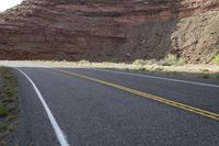 a person riding a motorcycle along a narrow road through rocks and sand cliffs a grassy area on both sides