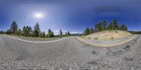 an asphalt road next to pine trees and mountains in a 3d vision lens view with a small camera