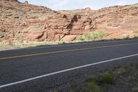 a person riding a motorcycle along a narrow road through rocks and sand cliffs a grassy area on both sides