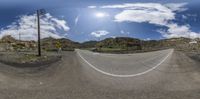 the sky and some mountains are full of clouds and blue skies, and there is a road with wires