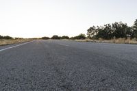 a long empty road with mountains in the distance with a car in the foreground