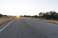 a long empty road with mountains in the distance with a car in the foreground