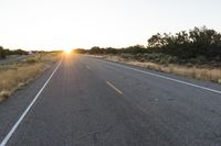 a long empty road with mountains in the distance with a car in the foreground