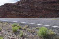 a person riding a motorcycle along a narrow road through rocks and sand cliffs a grassy area on both sides