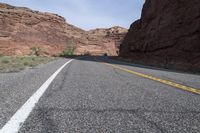 a person riding a motorcycle along a narrow road through rocks and sand cliffs a grassy area on both sides