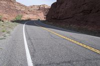 a person riding a motorcycle along a narrow road through rocks and sand cliffs a grassy area on both sides