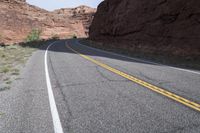 a person riding a motorcycle along a narrow road through rocks and sand cliffs a grassy area on both sides