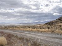 an old road stretches out into the desert with some mountains in the back ground on either side