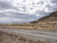 an old road stretches out into the desert with some mountains in the back ground on either side