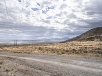 an old road stretches out into the desert with some mountains in the back ground on either side