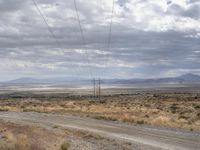 an old road stretches out into the desert with some mountains in the back ground on either side