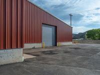 a red warehouse in front of a yellow post with three yellow poles and several windows