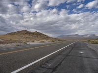 a empty road that is in the middle of a desert with mountain range behind it