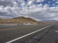 a empty road that is in the middle of a desert with mountain range behind it