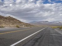 a empty road that is in the middle of a desert with mountain range behind it