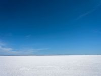 the empty snow field of a vast plain, looking at the sky and water below