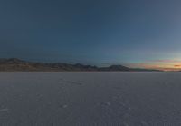 the landscape is barren and empty as the sun rises in the sky over the mountains