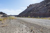 dirt road through a canyon with sparse vegetation in the foreground with hills in the background