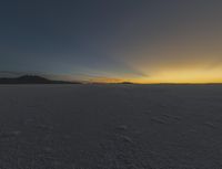 the sun is rising above a snowy plain, with no clouds and snow covering it