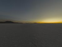 the sun is rising above a snowy plain, with no clouds and snow covering it