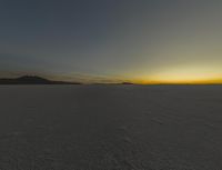 the sun is rising above a snowy plain, with no clouds and snow covering it