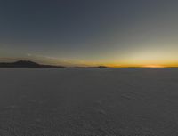 the sun is rising above a snowy plain, with no clouds and snow covering it