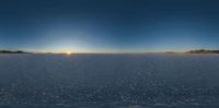 the sun is shining on the horizon of a snow covered field in a valley with rocky mountains