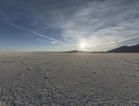 the sunset lights up the distance across the snow - covered desert landscape in the middle