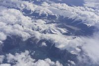 view from an airplane window looking at clouds and a blue sky above them as seen through a window