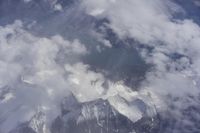 view from an airplane window looking at clouds and a blue sky above them as seen through a window
