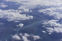 view from an airplane window looking at clouds and a blue sky above them as seen through a window