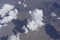 view from an airplane window looking at clouds and a blue sky above them as seen through a window