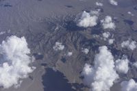 view from an airplane window looking at clouds and a blue sky above them as seen through a window