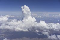 view from an airplane window looking at clouds and a blue sky above them as seen through a window