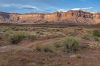 an empty dirt road through the desert with mountains in the background on a clear day