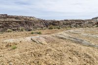 an area with dry grass and rocks, with desert like formations on the far side