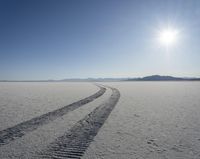 tire tracks from the back of a vehicle in a desert like area with mountains and sky